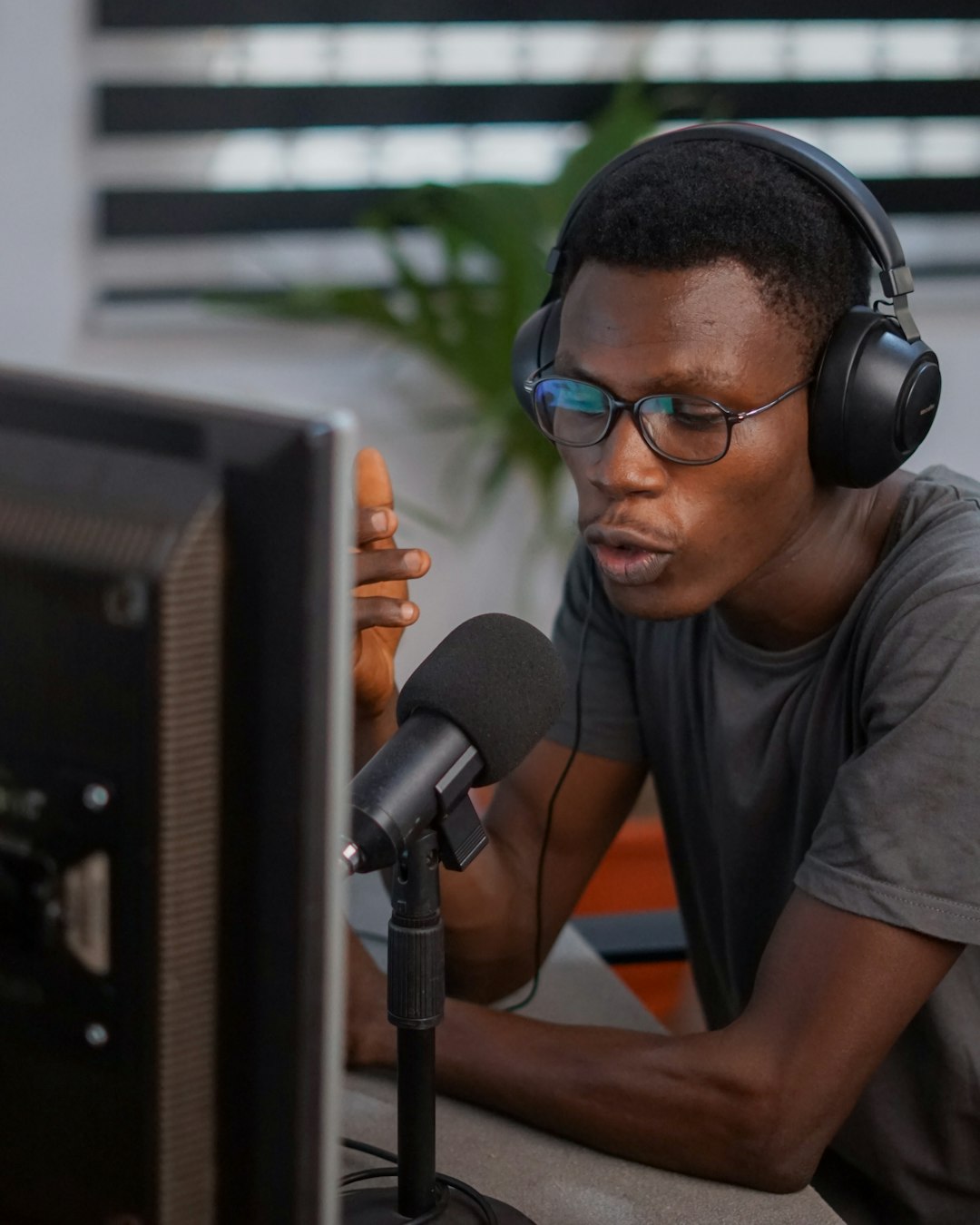 Crafting Captivating Headlines: Your awesome post title goes here African Man in Dark Crew Neck T-shirt Wearing Black Headphones Talking into Microphone Sitting in a Workspace Home Office